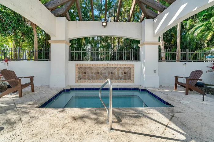 Inviting outdoor spa area surrounded by lush greenery, featuring elegant tile work and comfortable seating for relaxation.