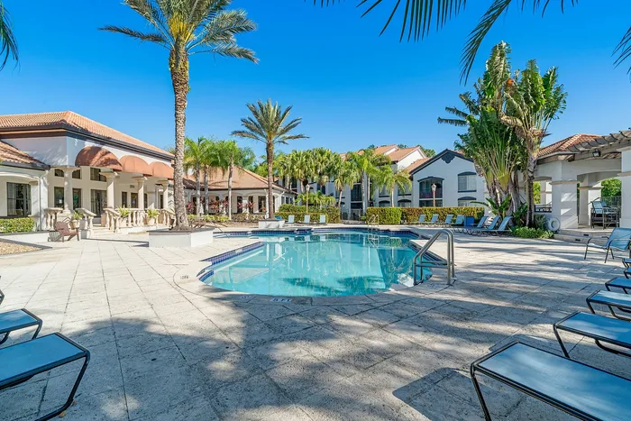 Luxurious resort-style pool area surrounded by lush palm trees and elegant architecture, perfect for relaxation and leisure.
