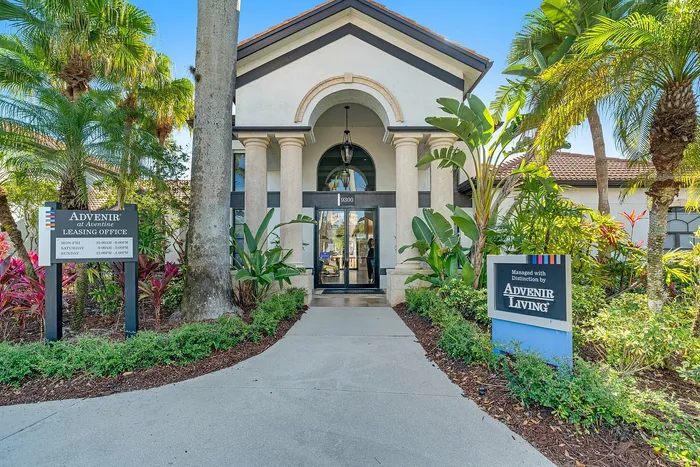 Inviting leasing office entrance surrounded by lush tropical plants, showcasing elegant architecture at Advenir Living.