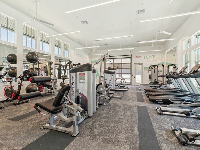 Bright and modern gym with state-of-the-art fitness equipment, showcasing treadmills, weight machines, and exercise bikes in a spacious interior.