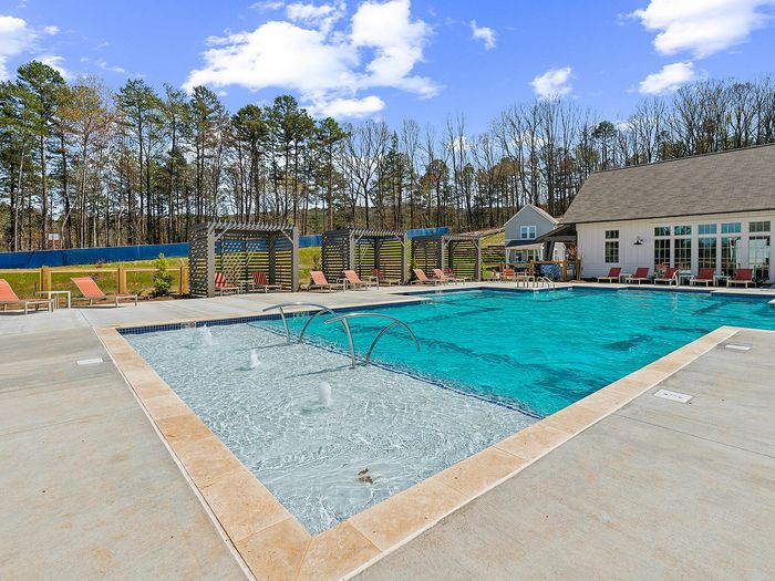 Inviting outdoor pool area with luxurious sun loungers, elegant pergolas, and crystal-clear water surrounded by lush greenery.