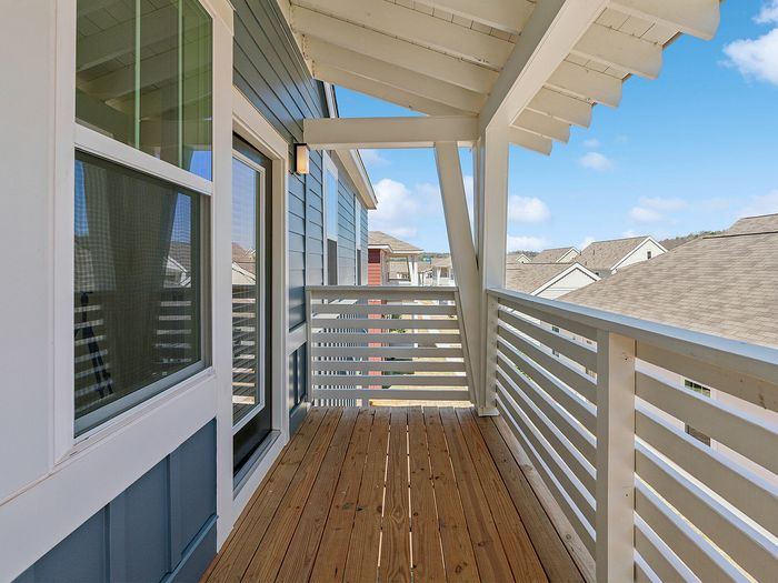Charming balcony with modern railing, offering a scenic view of a sunny suburban neighborhood.