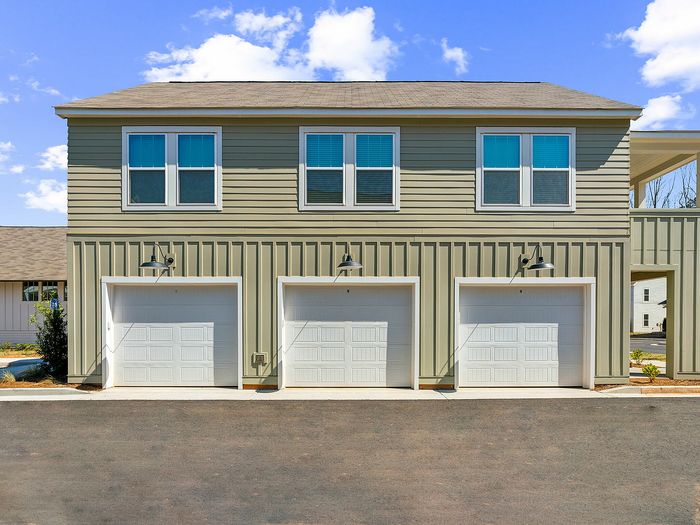 Charming modern duplex with three white garage doors, perfect blend of style and functionality. Bright windows enhance curb appeal.