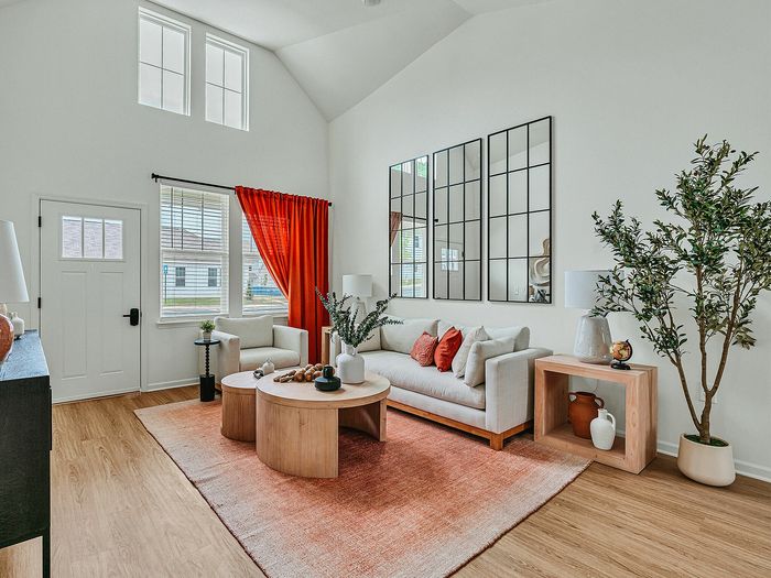 Bright and modern living room with high ceilings, large windows, and vibrant red accents creating a warm and inviting atmosphere.