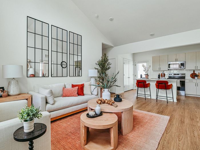 Chic open-concept living room with stylish decor, cozy seating, and a modern kitchen with bar stools, perfect for entertaining.