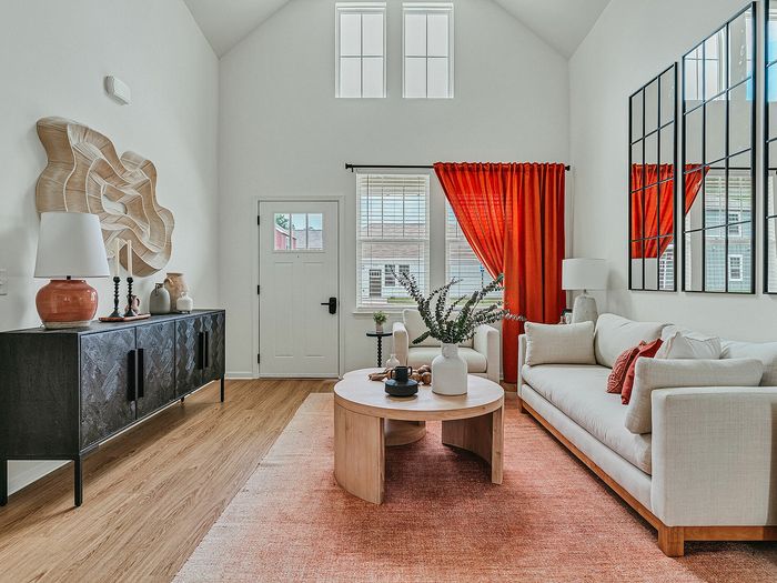 Inviting living room with high ceilings, contemporary decor, cozy white sofa, and vibrant red curtains complementing natural light.