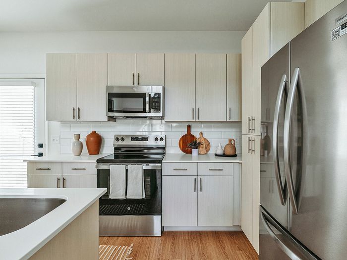 Chic modern kitchen with stainless steel appliances, sleek cabinetry, and stylish decor elements in a sunlit environment.
