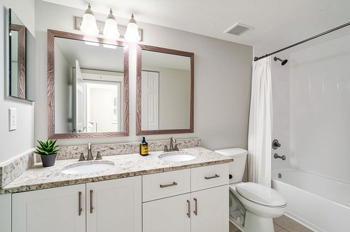 Bright modern bathroom with dual sinks, elegant granite countertops, and a sleek shower area.