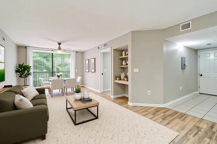 Bright and inviting living room with elegant decor, featuring a cozy sofa, stylish coffee table, and a dining area by large windows with lush greenery view.