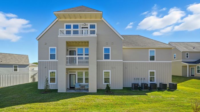 Charming two-story home with modern beige siding, inviting balconies, and a well-maintained green lawn under a bright blue sky.