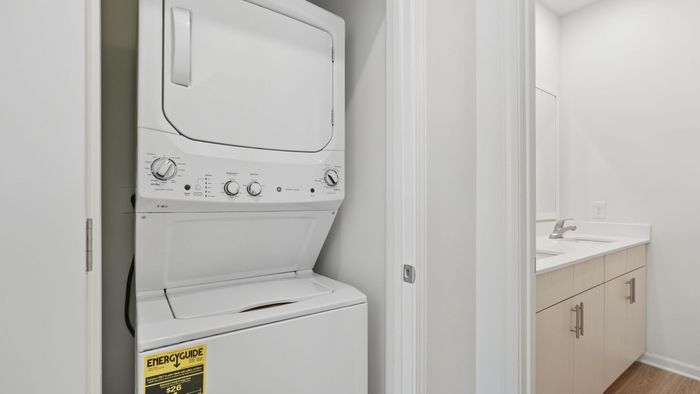 Modern apartment with a convenient in-unit stacked washer and dryer, adjacent to a sleek bathroom with elegant cabinetry and contemporary fixtures.