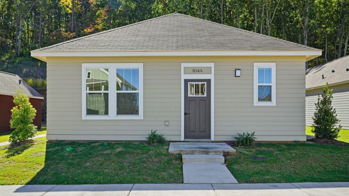 Charming single-story home with a welcoming front entrance, surrounded by lush greenery and nestled in a peaceful neighborhood.