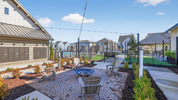 Charming apartment complex courtyard with cozy fire pit, inviting seating area, lush landscaping, and quaint pathways.