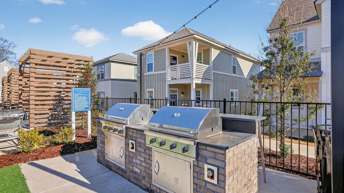 Modern outdoor bbq area with sleek grills and a charming apartment backdrop, perfect for social gatherings and relaxation.