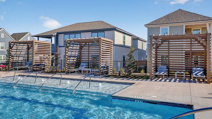 Modern poolside oasis featuring stylish cabanas and sparkling blue water, set against charming residential homes.