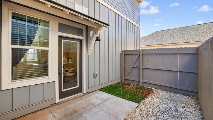 Charming enclosed patio with modern siding, glass door entrance, and quaint garden space, ideal for relaxation and entertaining.