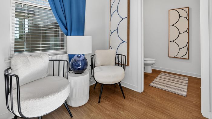 Chic apartment corner featuring plush chairs, elegant blue curtains, and modern artistic decor, perfect for relaxation.