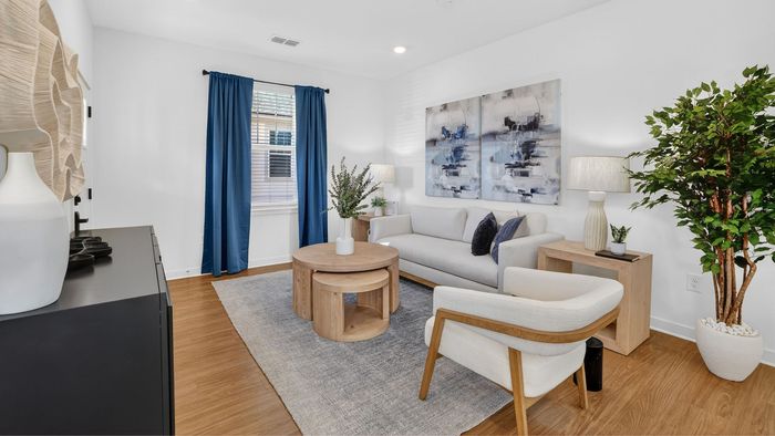 Chic living room with modern decor featuring a cozy white sofa, elegant wood furniture, vibrant blue curtains, and lush greenery.