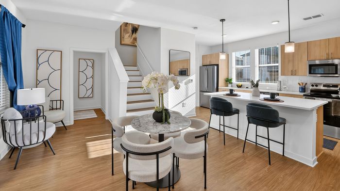 Modern open-concept living area featuring a stylish kitchen, elegant dining space, and cozy seating with natural light streaming through large windows.