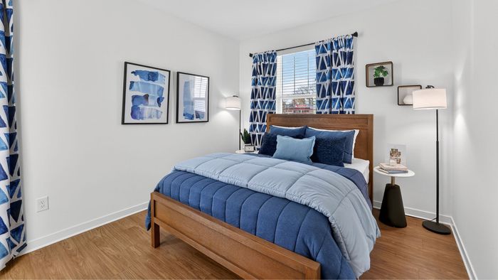 Bright and cozy bedroom showcasing stylish blue decor, elegant wooden furniture, and artistic wall art, bathed in natural light.