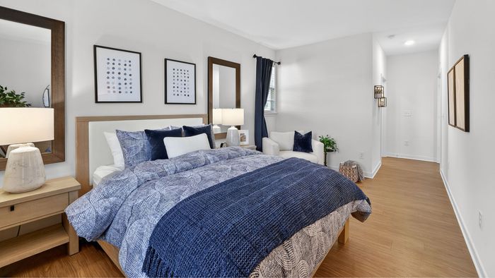 Inviting bedroom with elegant decor, featuring a plush bed with blue bedding, stylish artwork, and soft lighting.