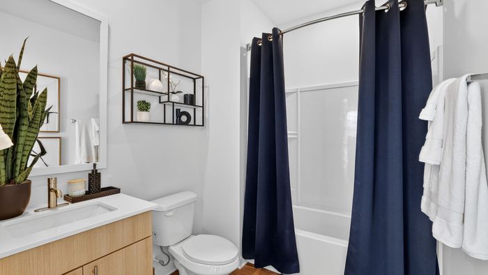 Modern bathroom with elegant navy curtains, sleek white countertops, and stylish decor accents.