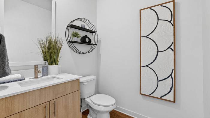 Modern bathroom with sleek wooden vanity, stylish wall art, and circular shelving with decorative accents.