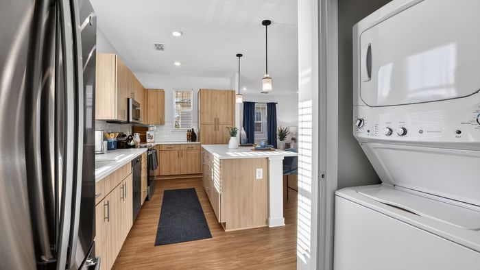Contemporary kitchen with sleek stainless steel appliances, elegant wood cabinetry, and a convenient in-unit washer and dryer.