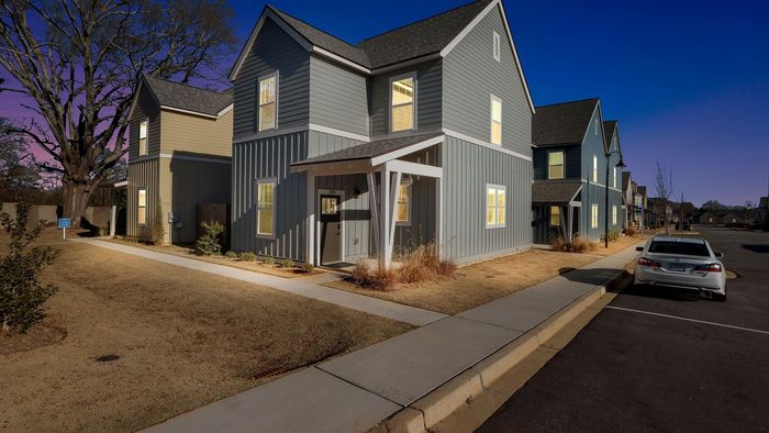 Charming modern two-story townhouse with inviting front porch, nestled in a serene and well-maintained neighborhood at dusk.
