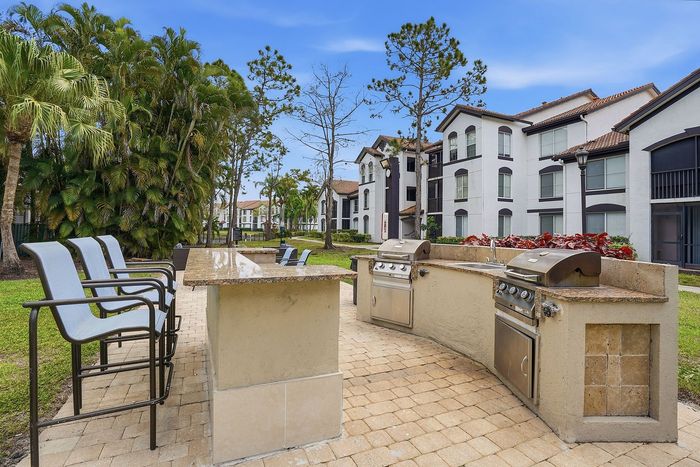 Inviting outdoor space with modern grills, lush greenery, and stylish seating, perfect for entertaining in an upscale apartment community.