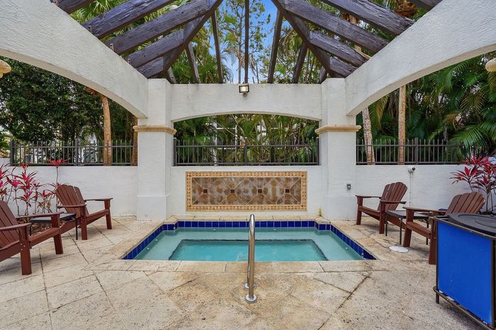 Charming outdoor spa area with a stylish hot tub, surrounded by lush greenery and elegant seating, offering a serene retreat.