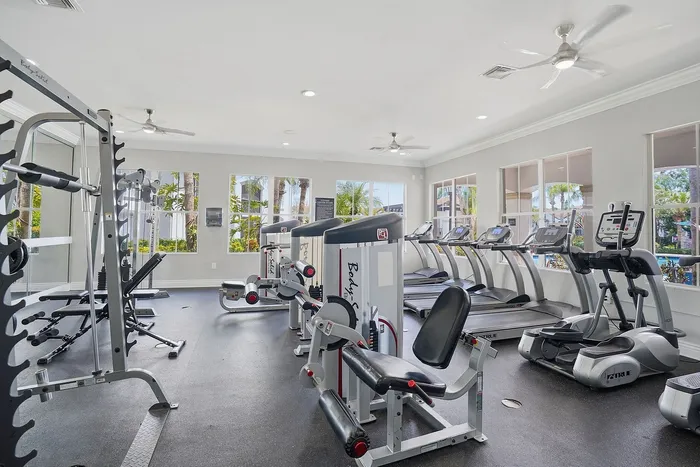 Bright, modern fitness center equipped with treadmills, weight machines, and large windows offering garden views.