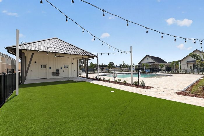 Inviting outdoor space with vibrant green lawn, modern pavilion, and sparkling swimming pool, ideal for relaxation and entertainment.