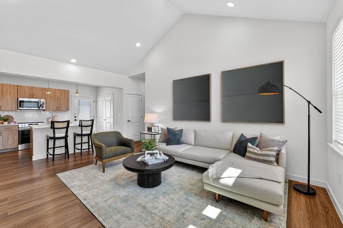 Bright open-concept living area with cozy sectional sofa, modern kitchen, and elegant decor, perfect for stylish city living.
