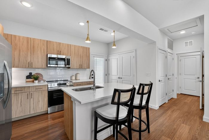 Modern kitchen with sleek wood cabinets, stainless steel appliances, and a spacious island with seating.