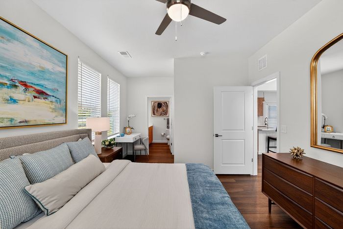 Bright and inviting bedroom with a modern plush bed, elegant artwork, and sleek furnishings, offering a tranquil retreat.