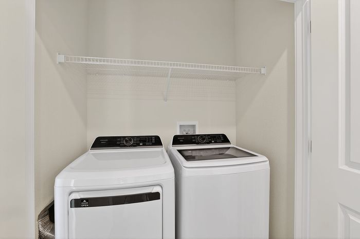 Bright laundry area featuring modern washer and dryer set with convenient shelving above, perfect for efficient living.