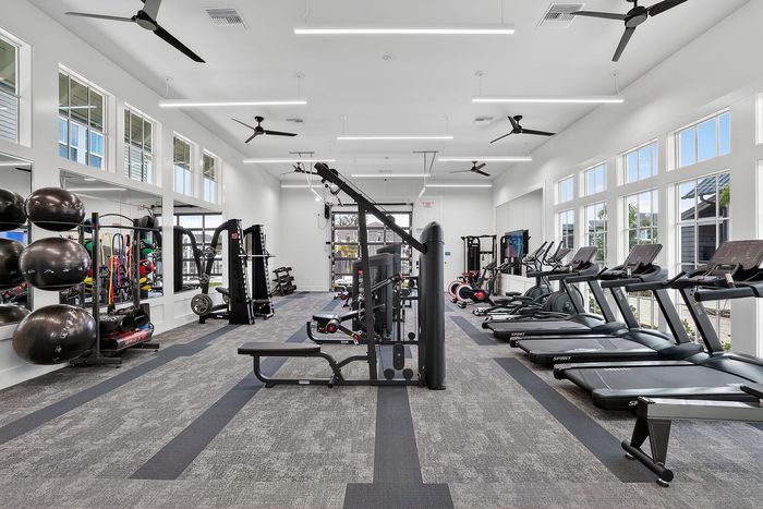Modern fitness center with state-of-the-art equipment, ample natural light, and a sleek, airy design.