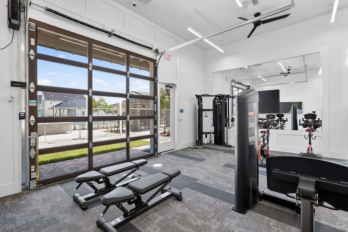 Bright and modern fitness center with state-of-the-art equipment, featuring large windows for ample natural light.