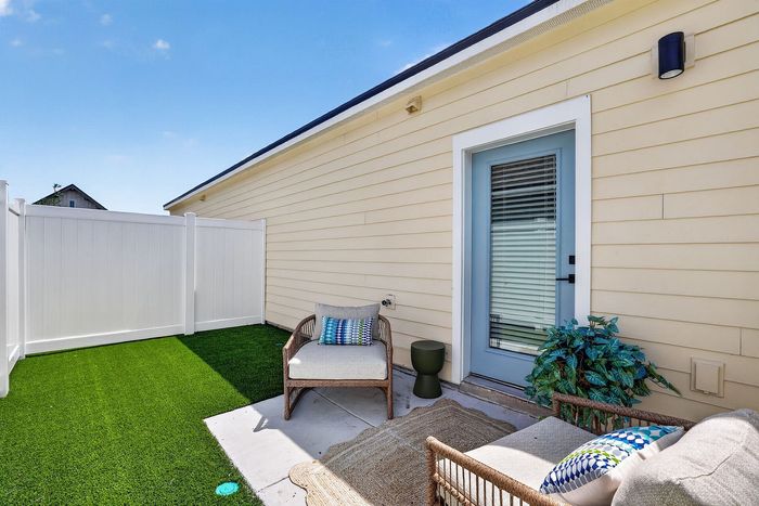 Charming backyard patio with cozy seating, vibrant green artificial grass, and stylish fence for privacy.