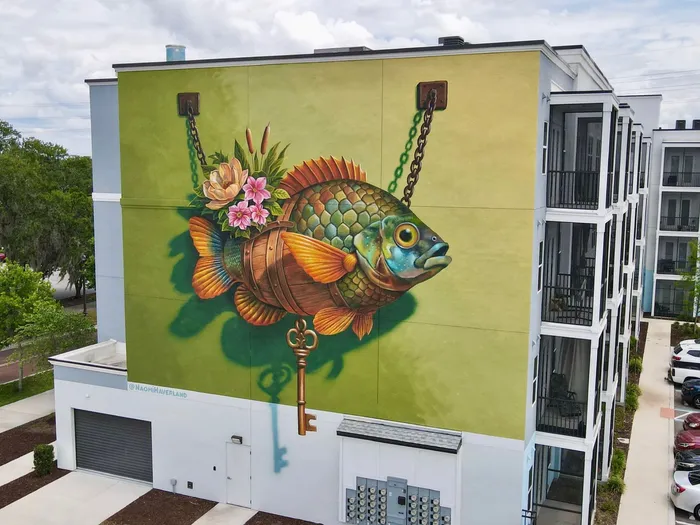 Modern apartment building featuring a vibrant mural of a colorful fish with floral accents and a hanging key detail.