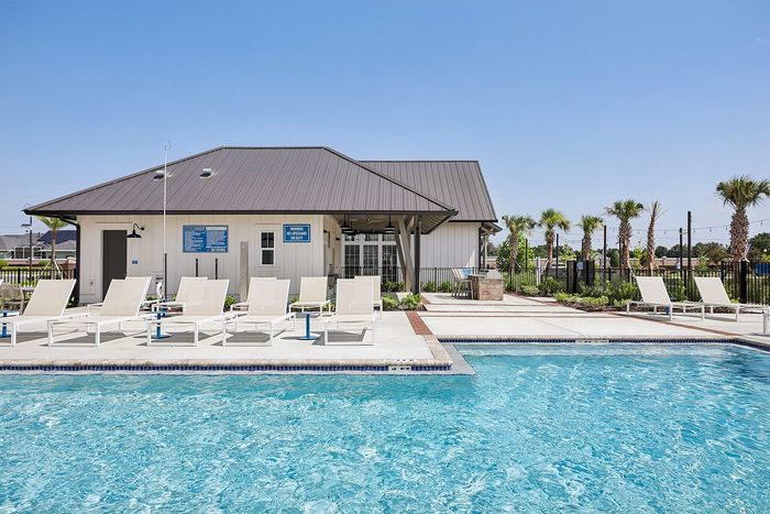 Inviting outdoor pool area with sun loungers and modern clubhouse surrounded by palm trees.
