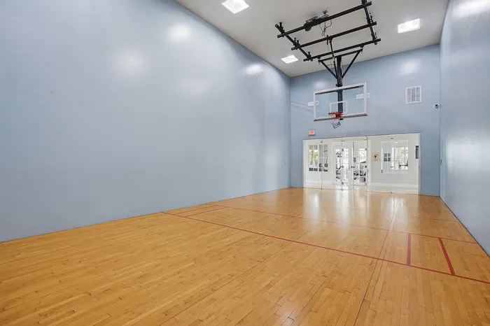 Spacious indoor basketball court with polished wooden flooring and modern lighting, perfect for sports enthusiasts.