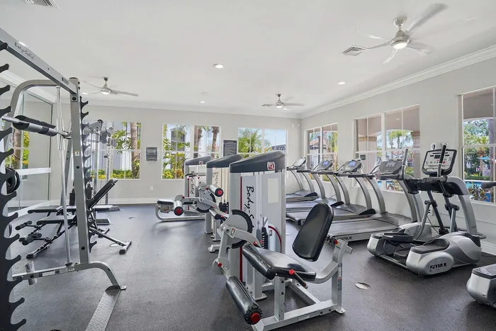 Bright and modern apartment gym with state-of-the-art fitness equipment, large windows, and lush outdoor views.