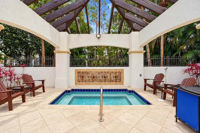 Elegant outdoor Jacuzzi area with stylish tile accents, surrounded by lush tropical greenery and comfortable seating.