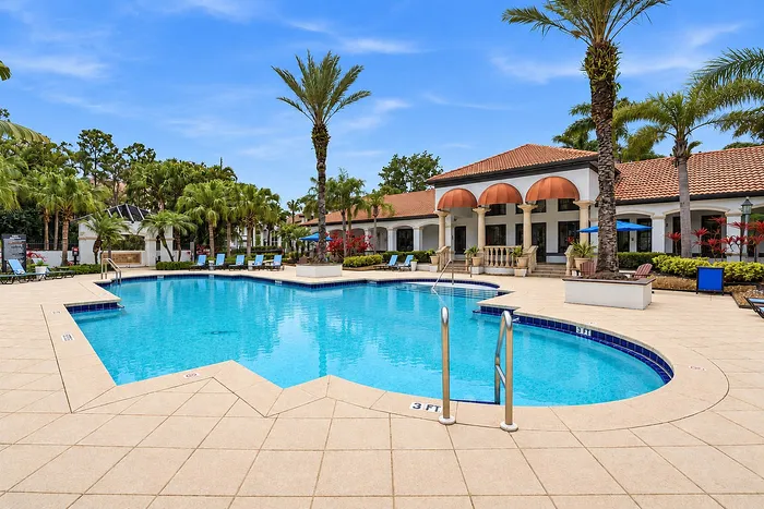 Luxurious outdoor pool surrounded by palm trees and elegant architecture, perfect for relaxation and leisure.