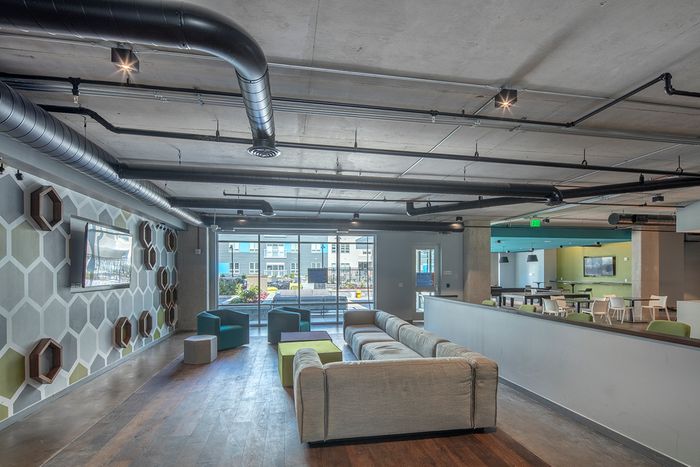 Lounge area in clubhouse with seating & flat-screen TV at Theory Syracuse | NY Apartments for Students