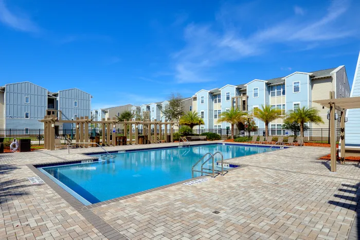 Sizable pool surrounded by pergolas | Palm trees and apartment buildings surround the pool area | Hawks Landing