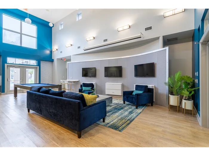 Multiple televisions set in front of a plush sofa | table set with chairs | Hawks Landing