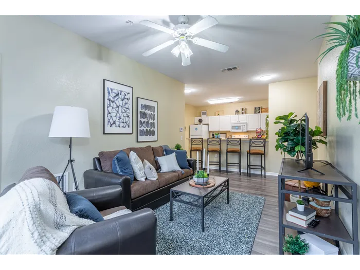 Interior view of the living room | Ample natural lighting accompanies a ceiling fan light fixture | entertainment center set in front of sofa and coffee table | Hawks Landing Apartments in Tampa, FL